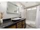 Updated bathroom with a vessel sink on a wooden vanity, and a tiled shower-over-tub with black hardware at 901 N Quartz St, Gilbert, AZ 85234
