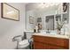 Cozy half bath featuring a wood vanity, white sink, and accessible toilet with support bars at 991 N Quail Ln, Gilbert, AZ 85233