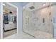 Glass enclosed shower with a bench, rainfall showerhead, and storage view of custom closet at 10694 E Redfield Rd, Scottsdale, AZ 85255