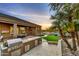 A wonderful outdoor kitchen and patio area with lush desert landscaping and mountain views at sunset at 10694 E Redfield Rd, Scottsdale, AZ 85255