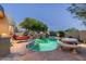 Desert backyard boasts a gorgeous pool with custom stone features, outdoor seating, and lush landscaping at 10822 E Prospect Point Dr, Scottsdale, AZ 85262