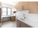 Spacious laundry room featuring modern cabinets, a desk and backyard views at 10918 W Dove Roost Rd, Queen Creek, AZ 85144