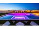 Inviting pool and spa area featuring colorful LED lighting, lounge chairs, and a cozy fire pit at twilight at 10918 W Dove Roost Rd, Queen Creek, AZ 85144