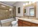Bathroom featuring a tub-shower combo with a glass enclosure and a wood vanity with a framed mirror at 11775 E Becker Ln, Scottsdale, AZ 85259