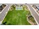 Aerial view of a well-maintained park with lush green grass, a basketball court, shade structures and desert landscaping at 12702 W Dove Wing Way, Peoria, AZ 85383
