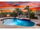 Beautiful pool and spa with rock features and mature landscaping under a dramatic sunset sky at 12702 W Dove Wing Way, Peoria, AZ 85383
