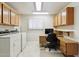 Bright laundry room with cabinetry, desk space, and modern washer/dryer set, offering convenience and efficiency at 12726 W Copperstone Dr, Sun City West, AZ 85375