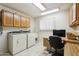 Functional laundry room with ample cabinet storage and a built-in desk, blending practicality and workspace at 12726 W Copperstone Dr, Sun City West, AZ 85375