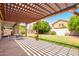 Spacious backyard features a stone patio with pergola, a well-maintained lawn, and mature trees for shade at 1432 W Hopi Dr, Chandler, AZ 85224