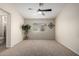 Bright bedroom with neutral carpet, a ceiling fan, and a large window at 15047 W Kings Dr, Surprise, AZ 85374