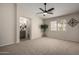 Spacious bedroom with neutral carpet, ceiling fan, and an ensuite bathroom at 15047 W Kings Dr, Surprise, AZ 85374