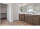 Bathroom vanity with double sinks, a large mirror, wood-look tile floors and an open closet at 18383 W Monte Lindo Ln, Surprise, AZ 85387