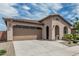 Inviting home featuring an attached two-car garage, neutral stucco siding, and beautiful desert landscaping at 23068 E Stacey Rd, Queen Creek, AZ 85142