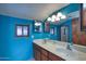 Bathroom featuring dual sinks with a marble countertop and abundant lighting, complemented by striking blue walls at 2424 E Ivy St, Mesa, AZ 85213
