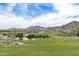 Scenic golf course view with lush green fairways, mature trees, and stunning mountain backdrop on a sunny day at 2701 N Black Rock Rd, Buckeye, AZ 85396