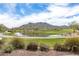 Picturesque view of the golf course with a tranquil pond and majestic mountain views in the distance at 2701 N Black Rock Rd, Buckeye, AZ 85396