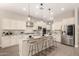 Bright kitchen featuring white cabinetry, large central island, stainless appliances, and breakfast bar at 2701 N Black Rock Rd, Buckeye, AZ 85396
