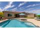 Inviting backyard pool with turquoise water, putting green, and blue patio umbrella at 2701 N Black Rock Rd, Buckeye, AZ 85396