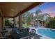 Covered patio with an outdoor dining table overlooking the pool, firepit, lounge area, and manicured landscaping at 2886 E Hazeltine Way, Chandler, AZ 85249