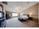 Expansive bedroom featuring plush carpeting, ceiling fan, and a stylish bed frame with a cushioned storage bench at 2886 E Hazeltine Way, Chandler, AZ 85249