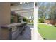 Outdoor kitchen and bar area featuring a tiled counter, grill, and outdoor seating, with a pergola and landscaped yard at 2886 E Hazeltine Way, Chandler, AZ 85249
