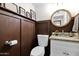 Stylish powder room with a wood-paneled wall, granite countertop, and round mirror at 2941 E Nisbet Ct, Phoenix, AZ 85032