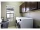 Functional laundry room featuring a modern washer and dryer, storage cabinets, and window at 3065 E Tamarisk St, Gilbert, AZ 85296