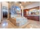 Bright bathroom featuring a central soaking tub with marble detail, wood cabinetry, walk-in closet, and tile flooring at 3118 W Glenhaven Dr, Phoenix, AZ 85045