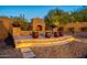 Outdoor fireplace on a raised stone platform with decorative pots, surrounded by gravel and landscaped greenery at 3118 W Glenhaven Dr, Phoenix, AZ 85045