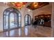 Grand foyer with a decorative ceiling fixture, marble floors, and ornate iron doors leading to outdoor space at 3118 W Glenhaven Dr, Phoenix, AZ 85045