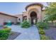 Ornate metal gate at the front entrance, framed by an arched entryway, desert landscaping, and stone accents at 3118 W Glenhaven Dr, Phoenix, AZ 85045