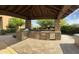 Outdoor kitchen with stone surround, stainless steel appliances, and covered space for outdoor dining and entertaining at 3118 W Glenhaven Dr, Phoenix, AZ 85045
