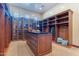 Spacious walk-in closet with custom wood built-ins, center island, and natural lighting at 3118 W Glenhaven Dr, Phoenix, AZ 85045