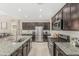 Open kitchen featuring stainless steel appliances, a granite island, and dark wood cabinetry at 37645 W Santa Clara Ave, Maricopa, AZ 85138
