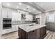 Elegant kitchen featuring white cabinets, stainless appliances, gray backsplash, and an island with a gray countertop at 42424 N Gavilan Peak Pkwy # 24206, Anthem, AZ 85086