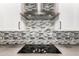 Modern kitchen with stainless steel hood, mosaic tile backsplash, and sleek black cooktop at 42424 N Gavilan Peak Pkwy # 24206, Anthem, AZ 85086