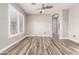 Neutral living room with gray walls, ceiling fan, wood-look tile floors, shuttered windows, and views of the hallway and doorway at 42424 N Gavilan Peak Pkwy # 24206, Anthem, AZ 85086