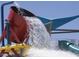 Waterpark with an overhead bucket dumping water onto a green and yellow slide with blue canopy at 42424 N Gavilan Peak Pkwy # 24206, Anthem, AZ 85086