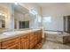 Bathroom features dual sinks, wooden cabinets, a large mirror, and a separate tub and glass-enclosed shower at 4772 E Agave Ln, Cave Creek, AZ 85331