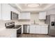 Bright kitchen features stainless steel appliances, white cabinets, and wood flooring at 5237 W Mountain View Rd, Glendale, AZ 85302