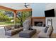 Inviting outdoor living space with comfortable seating, fireplace, ceiling fan and serene backyard views at 6648 E Horseshoe Rd, Paradise Valley, AZ 85253