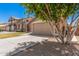 View of the home's front exterior and two-car garage with a mature tree in the front yard at 8037 W Mohave St, Phoenix, AZ 85043