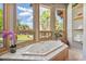 Bright bathroom featuring a soaking tub, large windows with views, and a tile surround at 8514 E Country Club Trl, Scottsdale, AZ 85255