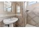 Well-lit bathroom with tiled walls, pedestal sink, and glass shower door at 9026 W Cambridge Ave, Phoenix, AZ 85037
