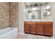 Bathroom featuring wood cabinetry, double sinks and tile-lined bath and shower at 9026 W Cambridge Ave, Phoenix, AZ 85037