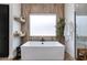 A freestanding tub is framed by a wood accent wall and a frosted window, creating a spa-like atmosphere at 100 W Northern Ave # 8, Phoenix, AZ 85021
