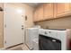 Functional laundry room including washer, dryer, and upper cabinets to provide convenient storage and cleaning at 1043 N 90Th Cir, Mesa, AZ 85207