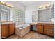 Bathroom featuring double vanities, soaking tub, and glass block window for natural light at 13134 W Los Bancos Ct, Sun City West, AZ 85375
