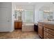Bathroom featuring double vanities, soaking tub, and glass block window for natural light at 13134 W Los Bancos Ct, Sun City West, AZ 85375