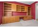 Spacious home office with custom built-in shelving and cabinetry on a red accent wall at 13134 W Los Bancos Ct, Sun City West, AZ 85375